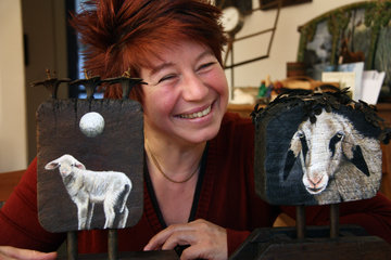 Die Künstlerin Heidi Theissen mit Gemälden von Schafen.